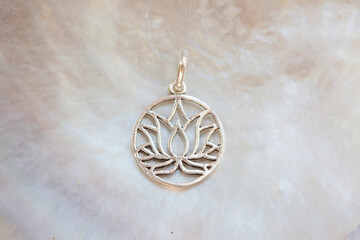 Fototapeta na wymiar Silver pendant in the shape of lotus on rocky background