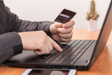Close-up Of A Man's Hand Holding Blank Credit Card During Using Laptop. Business concept and Online concept