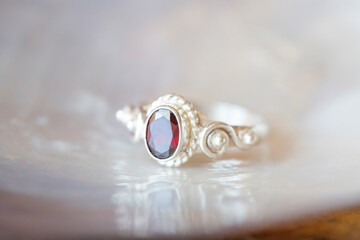 Elegant silver ring with garnet gemstone on rocky background