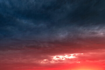 Obraz premium Colorful and dramatic sunset with red tinted clouds. Sky Background or texture