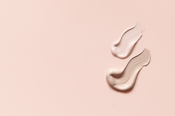 Makeup foundation cream strokes of different shades on skin tone color background. Nude pink creamy...