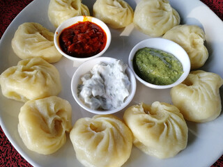 steamed Nepali traditional momos dumplings are served with different sauces. Close up, side view