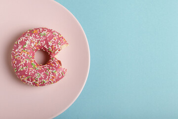 Donut on a pink plate on blue background.