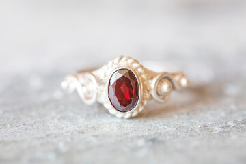 Elegant solver ring with garnet gemstone on rocky background