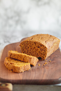 Fresh baked homemade pumpkin bread cut into slices on a cutting board with old knife. Selective focus with blurred foreground and background.