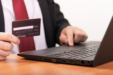 Close-up Of A Man's Hand Holding Credit Card During Using Laptop