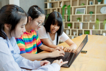 three asian teenager using laptop computer in home living room