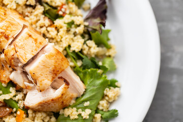 chicken with vegetables and quinoa on dish on ceramic background
