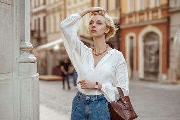 Street style photo of elegant fashionable woman wearing trendy white blouse, high waist jeans,...
