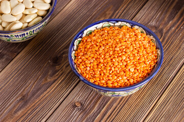 Red or orange lentil in a bowl on wooden background.