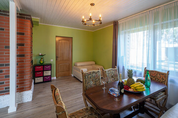 Contemporary interior of country private house. Green walls. Set table in living room. Wooden door. Cozy sofa.