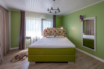 Contemporary interior of luxury bedroom in apartment. Front view of green bed. Private house.