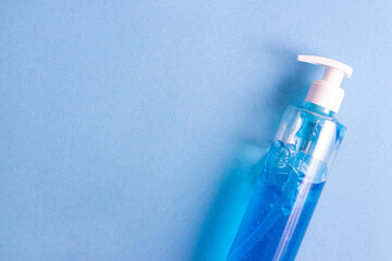 Flat lay bottle of sanitizing gel on blue background, free space for text