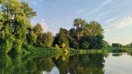 green lake shore in the rays of the evening sun