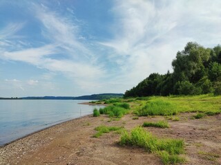blue cloudy sky over green river bank on sunny day
