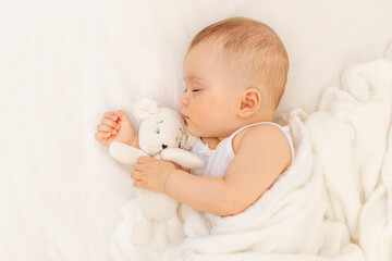 Small baby girl 6 months old sleeping in a white bed, healthy baby sleep