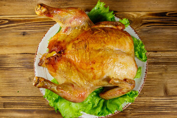 Baked whole chicken on a wooden table. Top view