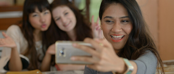 Obraz premium Three young beautiful women as friends together at the coffee shop