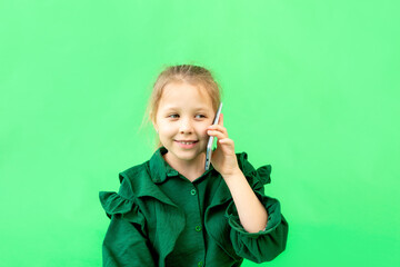 cute girl 7-9 years old talking on the phone on a green isolated background, portrait, place for text