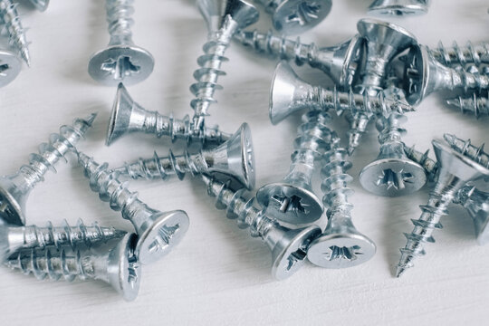 Metal tapping screws for wood on white wooden background. Construction equipment concept. Top view. Copy, empty space for text