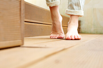 Beautiful bare female feet. A woman is standing barefoot on wooden floorboards.