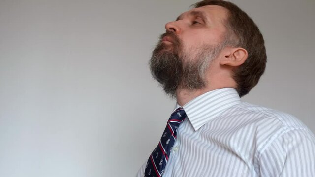 Mature man with beard wearing formal clothes takes pills and can hardly swallow them. Being healthy