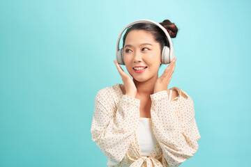 Teenage girl wearing headphones making gesture against blue background.