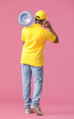 African-American delivery man with bottle of water talking by mobile phone on color background, back view