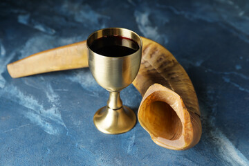 Shofar and sacramental goblet with wine on color background. Rosh Hashanah (Jewish New Year) celebration