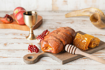 Challah with honey, pomegranate and sacramental goblet with wine on table. Rosh Hashanah (Jewish New Year) celebration