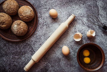 ingredients for baking rye buns, rolling pin, eggs, flour, mixer on gray background