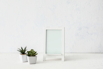 Photo frame with houseplants on table in room