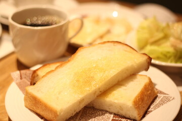 Fototapeta na wymiar Close up of a plate of delicious hot toast bread served with a cup of hot coffee, soft focus