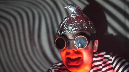 Insane men wearing a tin foil hat to protect himself from the 5g waves hitting his brain being afraid and scarred looking around him. Conspiracy theory making a person loose touch with reality.