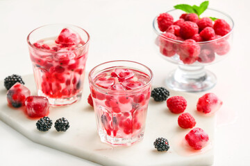 Glasses with ice and frozen berries on white background
