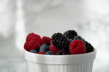 Berries in white jar on marble sfonfo