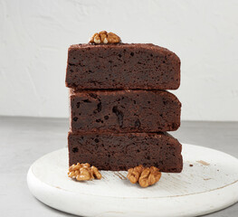 stack of baked pieces of brownie chocolate cake with nuts on a wooden board