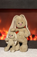 Family of rabbits near the fireplace. Soft toys of bunnies.