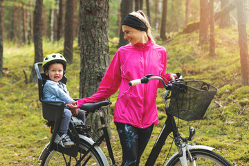 Obraz premium happy mother with son in bike child seat cycling on forest trail