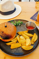 Big tasty burger and fries with beer on background on the wooden table