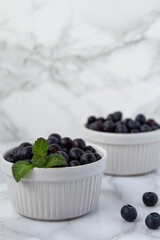 Bluberries fresh in a white bowls with mint front view