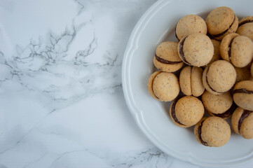 Baci di dama, lady kisses, on white plate Italian biscuits whit chocolate, marble background 