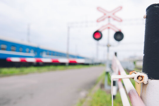 Railway crossing with a red traffic light on the background of the train.