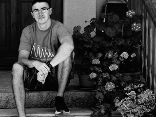 Portrait of a young man sitting on stairs in front of church.