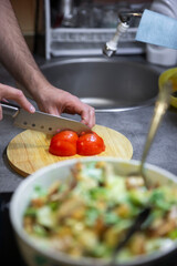 Preparation of juicy salad with chicken, iceberg lettuce and tomatoes.