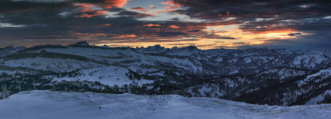 Amazing sunset alpenglow panorama view to snow covered mountain ranges and dramatic sky in cold winter. View from Riedberger Horn to Allgau Alps Mountains, Ifen and Austria. Bavaria, Germany.