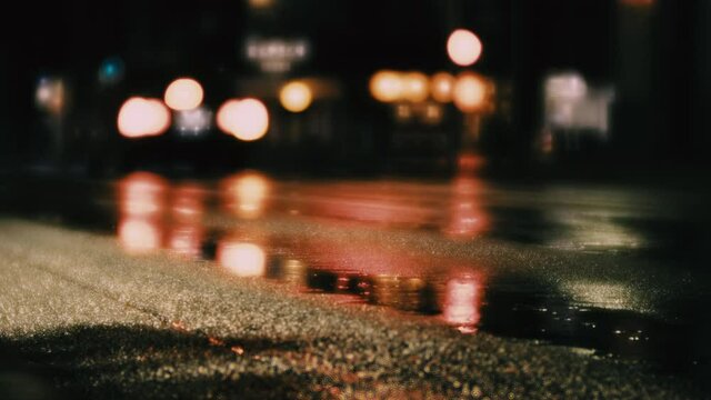 【雨】夜の車道の水溜まりにライトが反射する様子　交通イメージ
