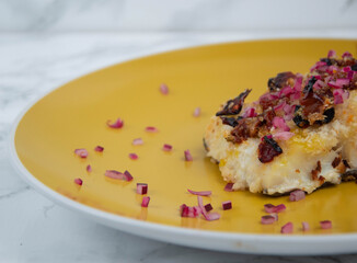 Cod fish with red onion on yellow plate, marble backgound