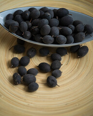 Velvet tamarind fruit ( Dialium cochinchinense) or buah keranji in a wooden bamboo plate background.
