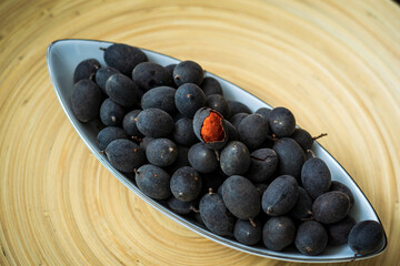 Velvet tamarind fruit ( Dialium cochinchinense) or buah keranji in a wooden bamboo plate background.